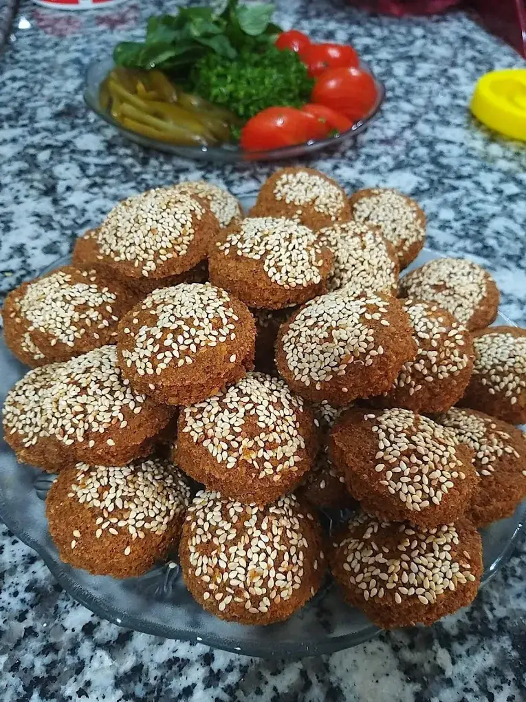 Teller mit sesambestreuten, knusprigen Falafel-Bällchen, Pickles und Tomaten